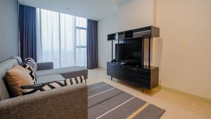 A modern living room with a sofa, a flat-screen TV, and a dark entertainment unit. - Modern and Spacious 2BR L'Avenue Apartment (Jakarta)