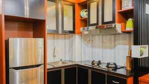 Una cocina compacta con un refrigerador de acero inoxidable, un lavamanos y una estufa.