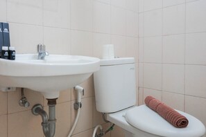Une salle de bain avec un lavabo, des toilettes et une serviette posée sur la lunette.