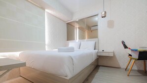 Moderni hotellihuone, jossa on sänky, yöpöytä ja tuoli.
