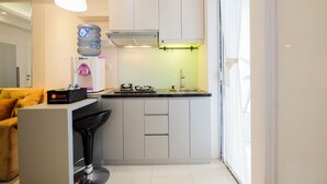 A compact kitchen with a water dispenser, a coffee machine, and a gas stove.