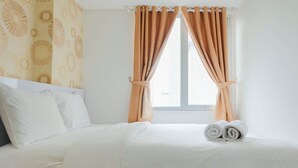 A neatly made bed with white linens and a pair of rolled towels on the side. - 2BR Homey Apartment at Bassura City near Mall (Jakarta)
