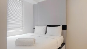 A modern hotel room with a large bed, white bedding, and a neatly made bed with a rolled towel. - Stylish and Modern 2BR Bassura City Apartment (Jakarta)