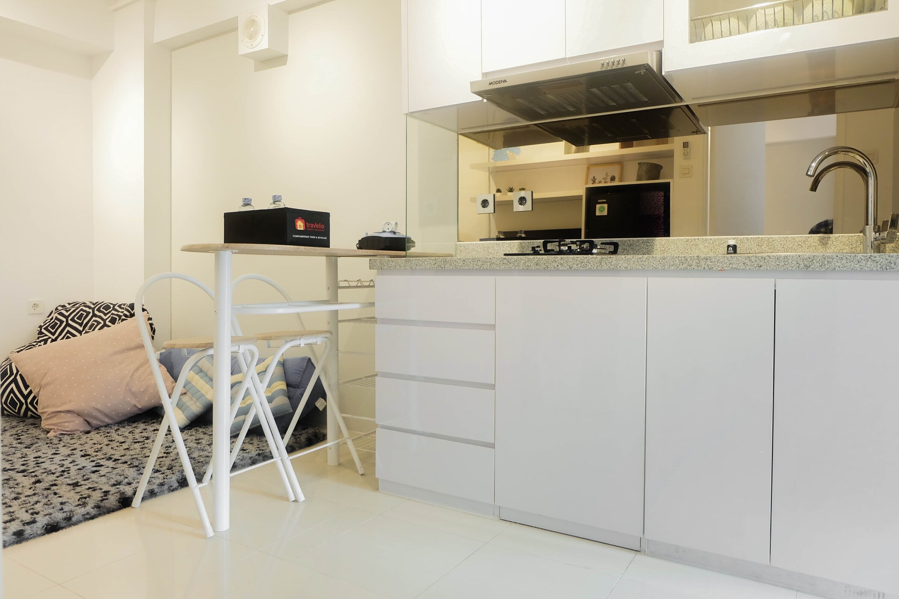 A modern kitchen with white cabinetry, a stainless steel range hood, and a countertop with a built-in stove.