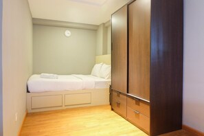 A bedroom with a bed, a wardrobe, and a wall clock. - Exclusive and Spacious 1BR Apartment at Bassura City (Jakarta)