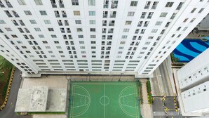 A high-rise building with multiple balconies and a rooftop basketball court. - Exclusive and Spacious 1BR Apartment at Bassura City (Jakarta)