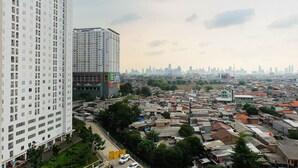 A high-rise building with multiple floors and a mix of residential and commercial structures in the background. - Tidy Studio Apartment at Bassura City near Shopping Mall (Jakarta)