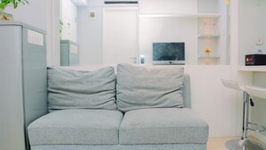 Ett modernt vardagsrum med en grå soffa, en tv och en vit handfat.