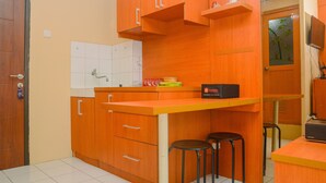A compact kitchen with wooden cabinets, a countertop, and two stools.