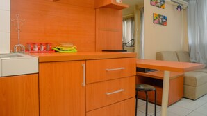 A compact kitchen with wooden cabinets, a small dining table, and a sofa.