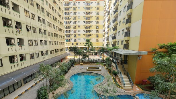 A multi-story residential building with balconies, a central courtyard with a swimming pool, and a covered walkway.