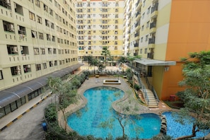 Un edificio residencial de varios pisos con balcones, un patio central con piscina y un corredor cubierto.