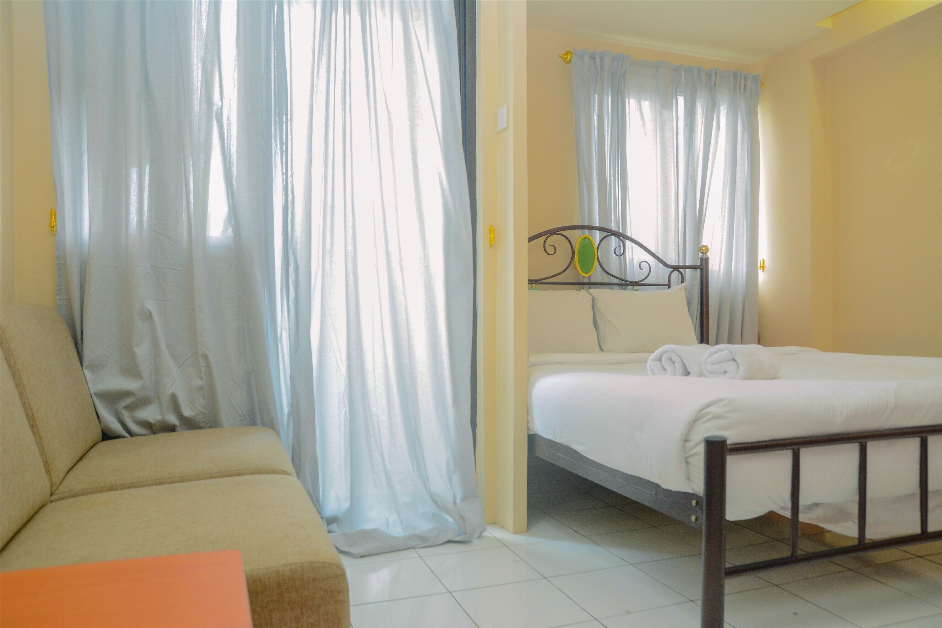 A bedroom with a bed, a sofa, and curtains.