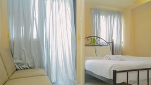 A bedroom with a bed, a sofa, and curtains.