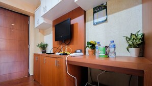 A hotel reception area with a wooden desk, a flat-screen TV, a calendar, and potted plants. - Comfy Studio Room Apartment at Kebagusan City (Jakarta)
