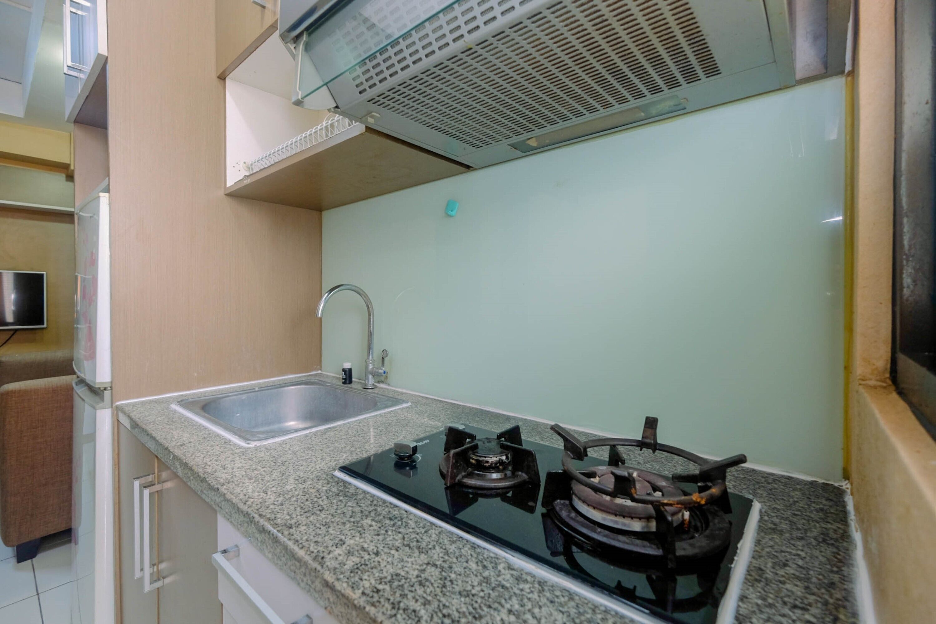 A kitchen with a gas stove, sink, and a stainless steel refrigerator.