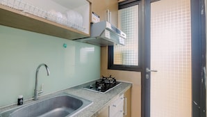A compact kitchen with a sink, gas stove, and a window with a view. - Warm and Homey 2BR Apartment at Kebagusan City (Jakarta)