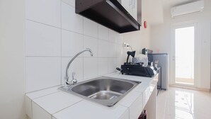 Een moderne keuken met een roestvrijstalen spoelbak, witte betegelde wanden en een zwarte afzuigkap.