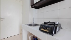 Een keuken met een wit aanrecht, een spoelbak en een zwarte Rinnai gasoven.