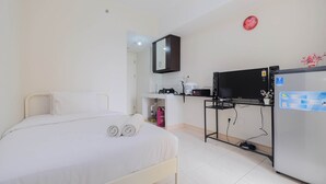 Een hotelkamer met een bed, een televisie, een koelkast en een kitchenette.