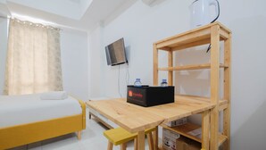 Een kamer met een bed, een houten bureau, een televisie en een wandplank.