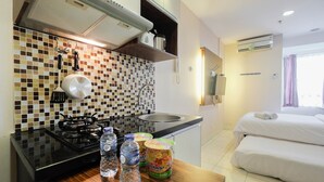 A compact hotel room with a kitchenette, a bed with white linens, and a bathroom with a shower.