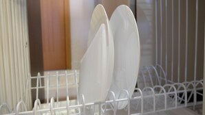A white metal rack with white plates and bowls.