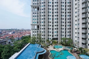 A high-rise building with multiple balconies and a rooftop pool area with a small waterfall feature. - 2Bedroom Sky Terrace Apartment with Pool View (Jakarta)