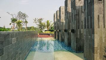 A pool area with a tiled floor and a low wall on one side.