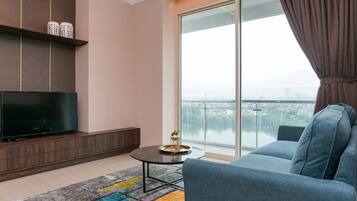 A modern living room with a flat-screen TV, a sofa, a coffee table, and a large window with a view of a cityscape.