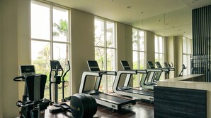 A gym with treadmills, elliptical machines, and a weight bench. - Cozy and Comfy 2BR Citralake Suites Apartment (Jakarta)