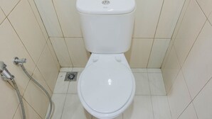 Een wit toilet met een douchetoilet in een betegelde badkamer.