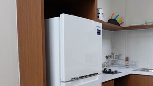 Een keuken met een witte koelkast, houten kastjes en een wit aanrecht.