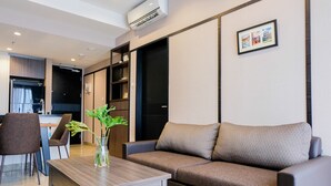 A modern living room with a sofa, a coffee table, and a dining area with chairs.