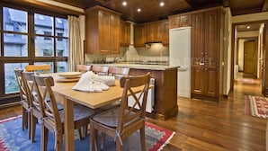 A wooden kitchen with a dining table and chairs, wooden cabinets, and a refrigerator. - Abetos - Val de Ruda (Baqueira)