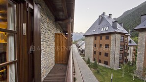 A stone building with a wooden balcony, a stone wall, and a view of a mountain. - Abetos - Val de Ruda (Baqueira)
