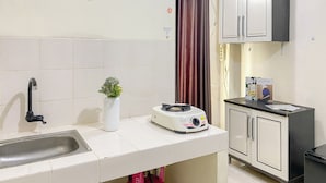 A kitchen with a sink, a small plant, a rice cooker, and cabinets. - Strategic Studio Apartment at Casablanca East (Jakarta)