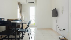A room with a dining table, chairs, a TV mounted on the wall, and an air conditioning unit. - Comfy 2BR Apartment @ Springlake Summarecon (Bekasi)