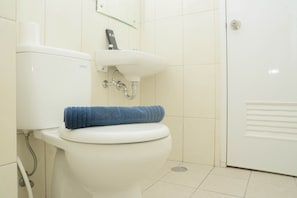 A toilet with a blue towel on it, a white sink, and a door with a handle. - Comfy 2BR Apartment @ Springlake Summarecon (Bekasi)