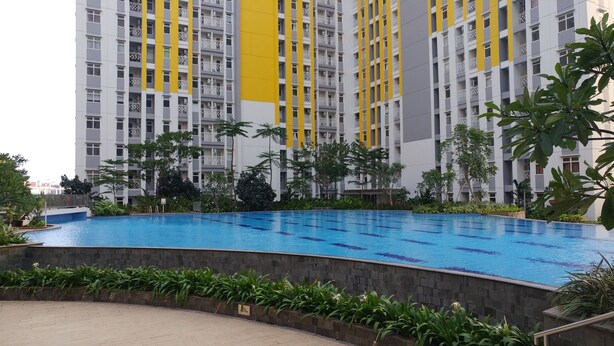 Une piscine entourée de verdure et un immeuble de grande hauteur agrémenté de touches de couleur jaune.