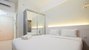 Ein Hotelzimmer mit einem großen Bett, einem Kleiderschrank, einem Spiegel und einer Wandleuchte.