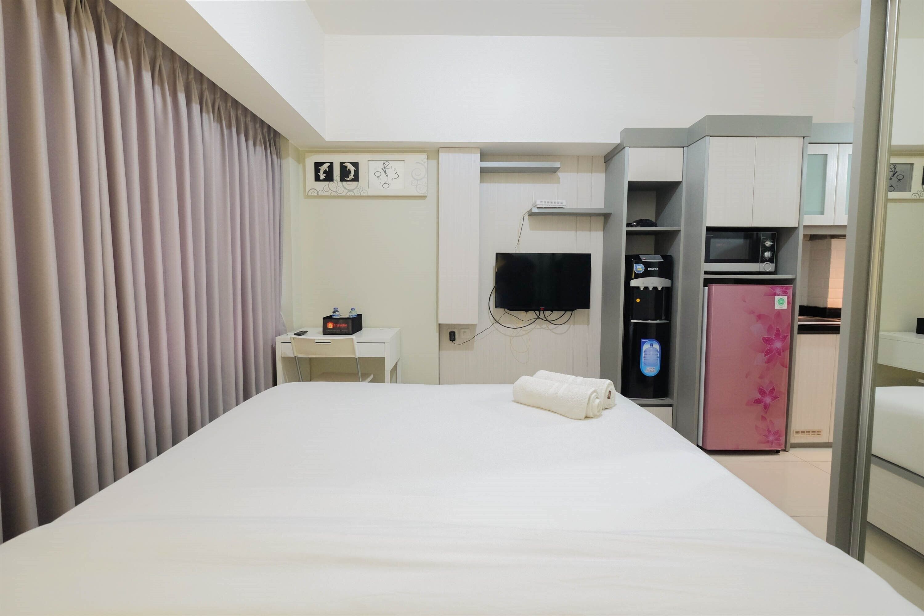 Une chambre d’hôtel équipée d’un lit, d’un bureau, d’une télévision, d’un mini-bar et d’un réfrigérateur.