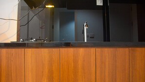 A wooden counter with a sink and a mirror reflecting a faucet. - Comfy Studio Room at Patraland Urbano Apartment (Bekasi)