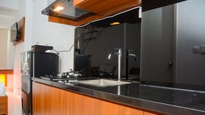 A modern kitchen with a stainless steel sink, a built-in stove, and a wooden cabinet. - Comfy Studio Room at Patraland Urbano Apartment (Bekasi)