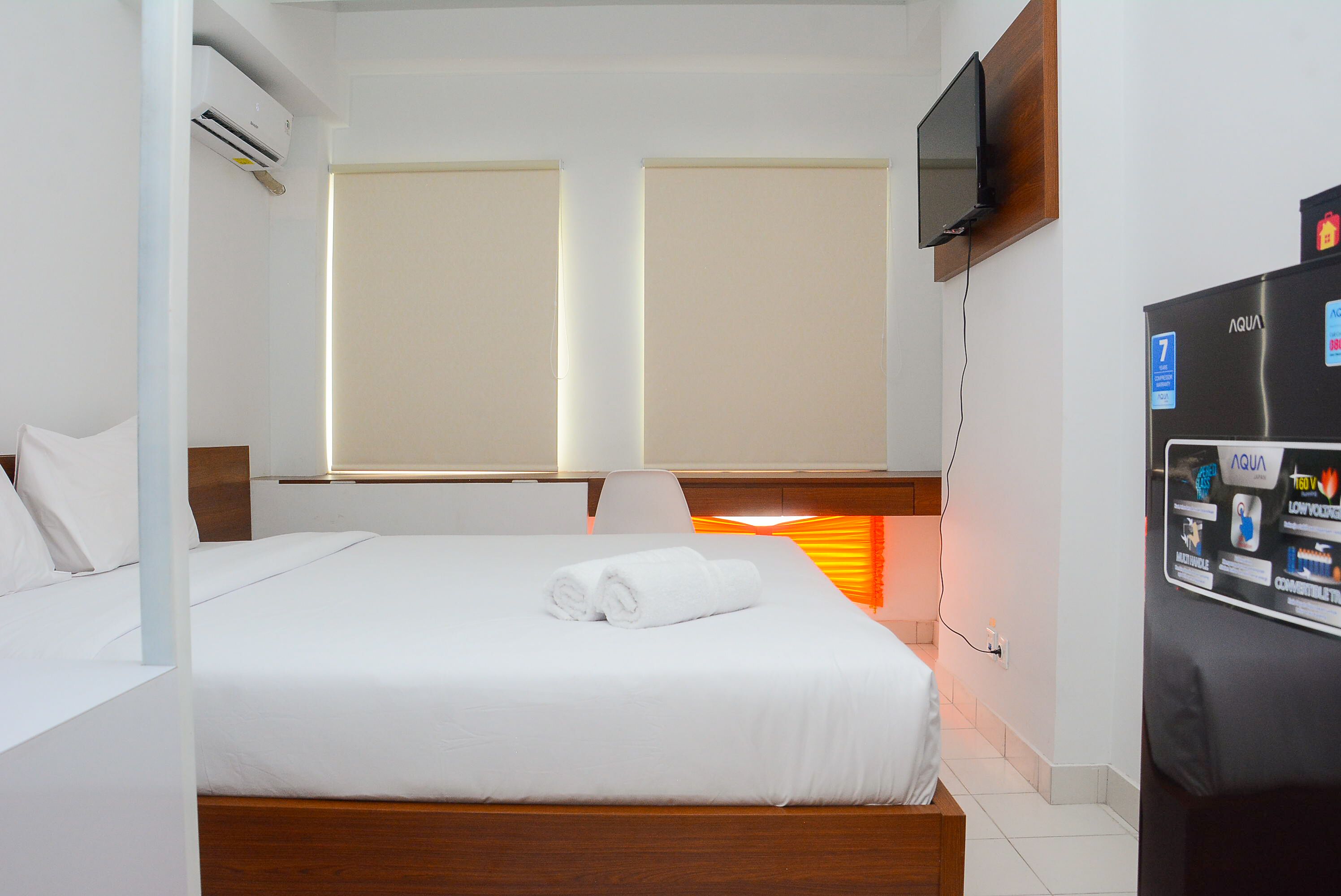 Une chambre d’hôtel équipée d’un lit, d’un téléviseur fixé au mur et d’un réfrigérateur.