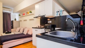 A compact kitchen with a black countertop, white cabinets, and a built-in stove. - Pool View and Homey 2BR Apartment @ Springlake Summarecon (Bekasi)