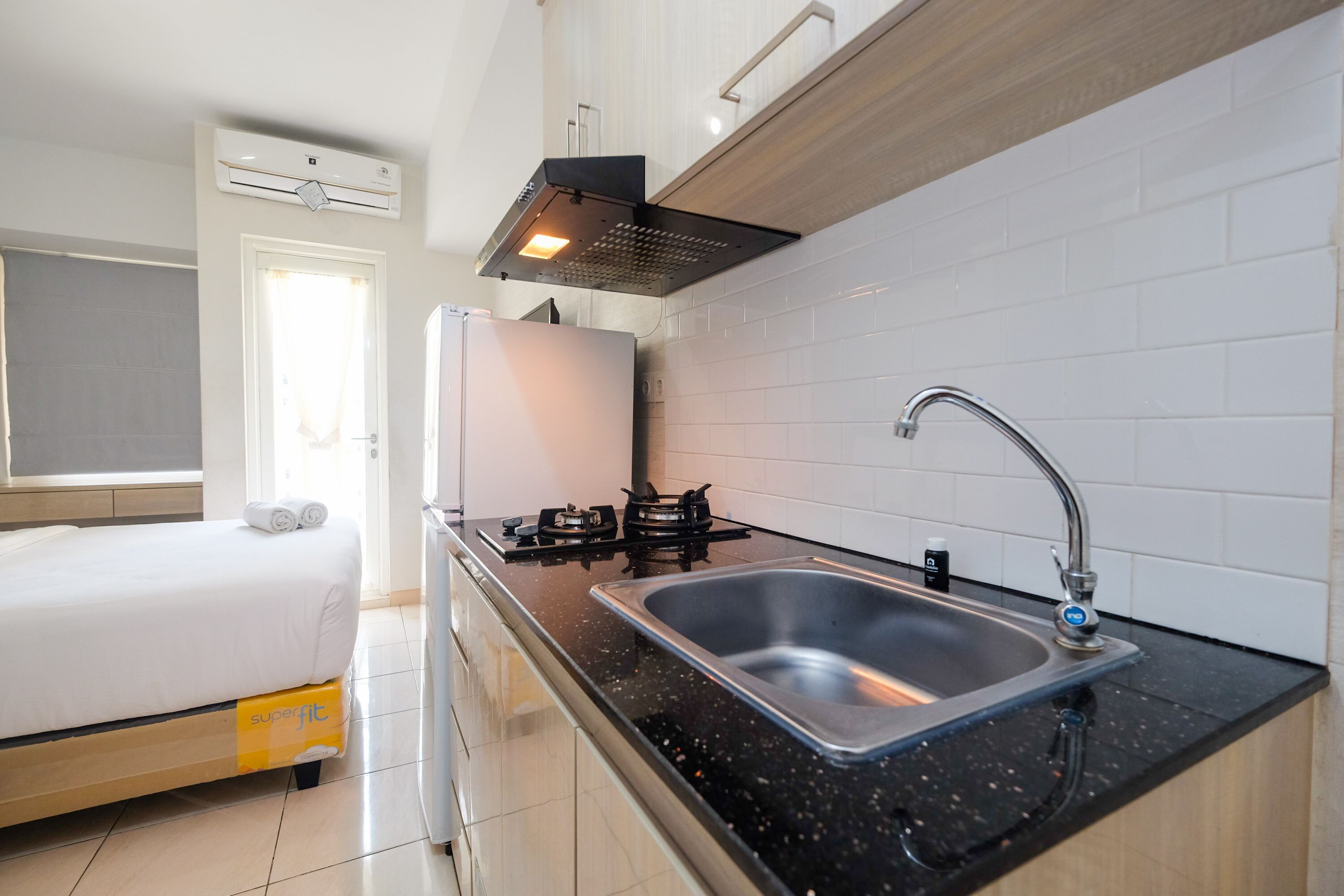 A compact kitchen with a sink, stove, and a bed in the adjacent room.