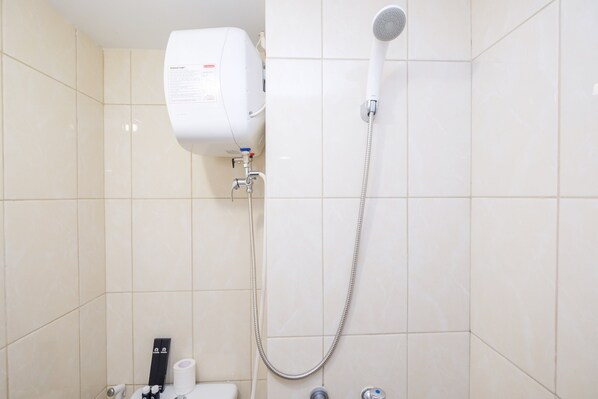 A bathroom with a white shower, a toilet, and a hand dryer.