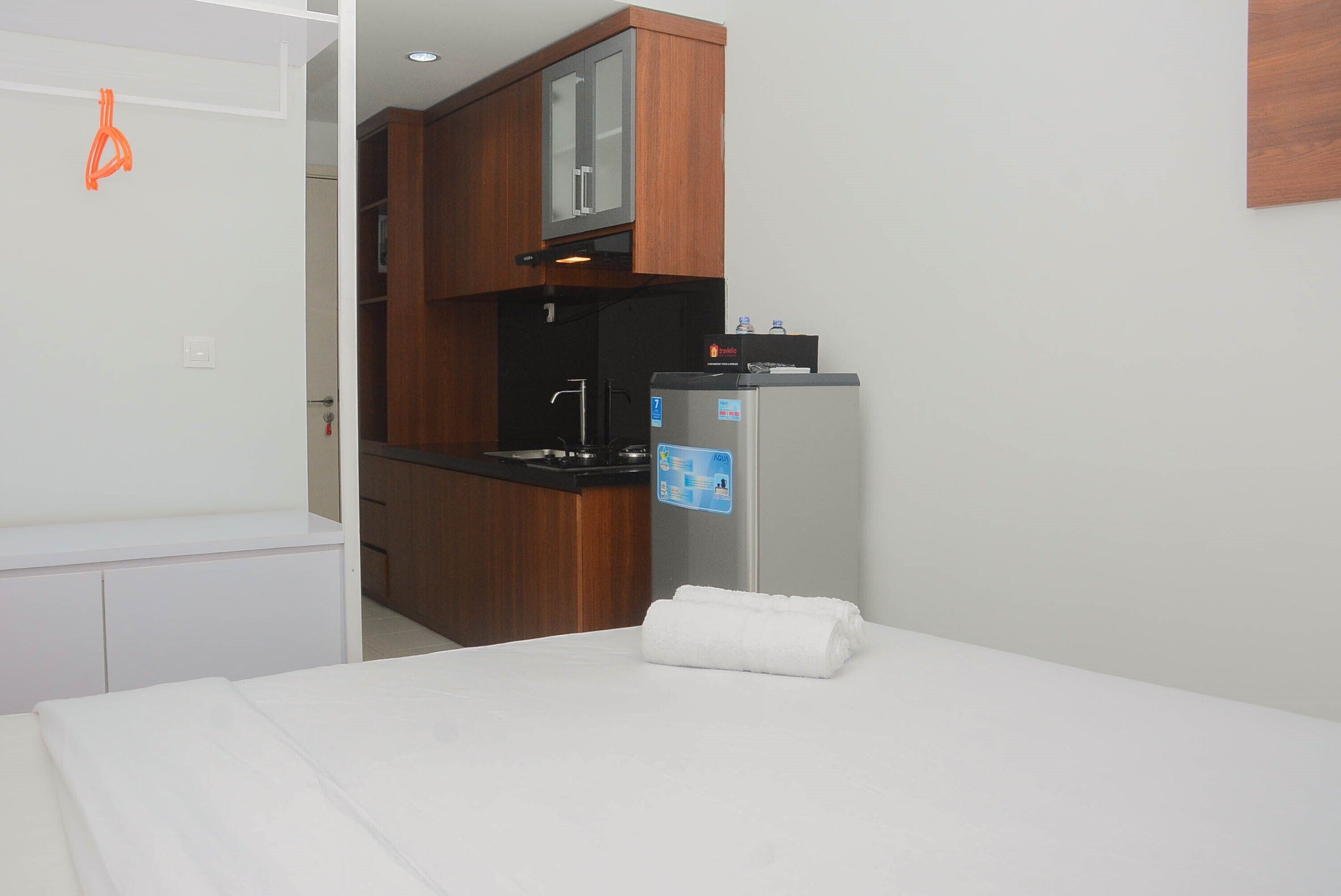 Una habitación de hotel con cama, una kitchenette pequeña y un refrigerador.