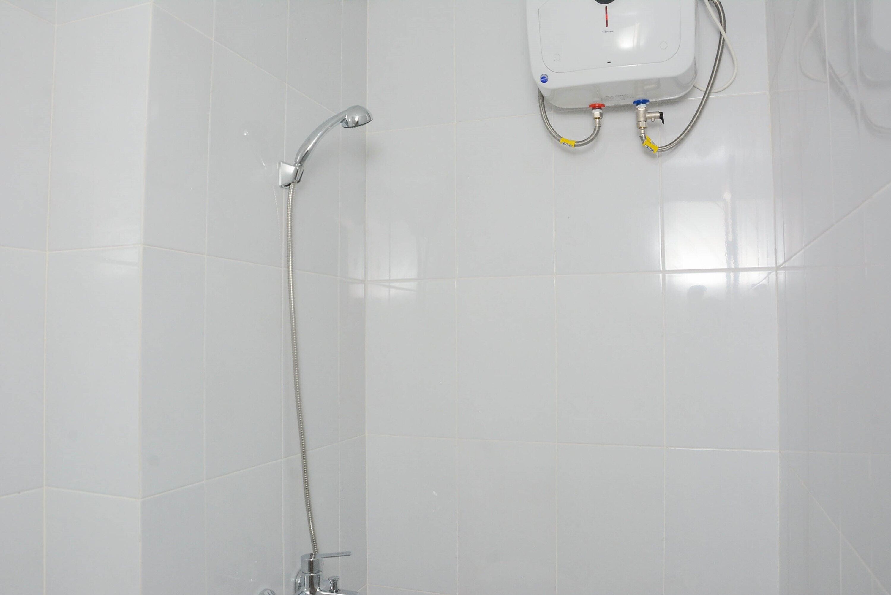A shower with a handheld hose and a wall-mounted control panel.